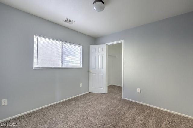 unfurnished bedroom with a spacious closet, a closet, and carpet flooring