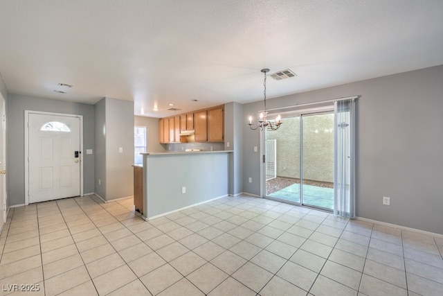 kitchen with kitchen peninsula, light tile patterned floors, plenty of natural light, and a notable chandelier