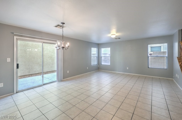 tiled empty room featuring a chandelier