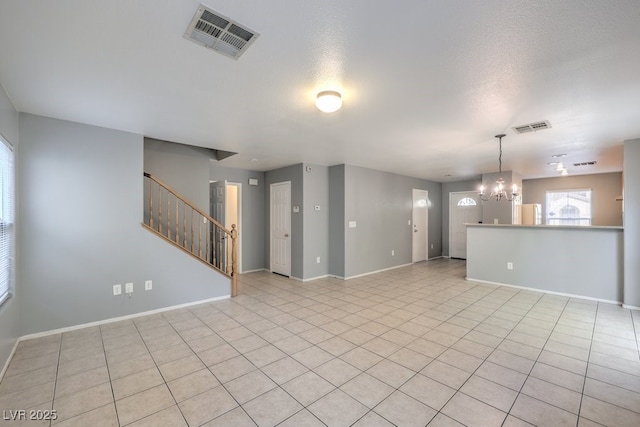 empty room featuring a textured ceiling, an inviting chandelier, and light tile patterned floors