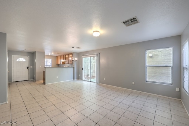 unfurnished living room featuring light tile patterned floors, a wealth of natural light, and an inviting chandelier