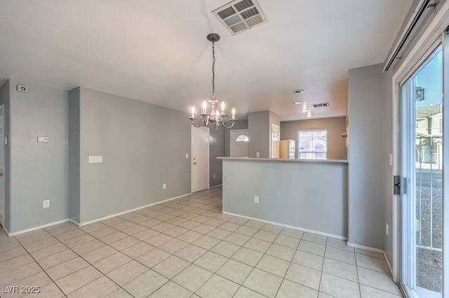 empty room featuring light tile patterned flooring and a chandelier