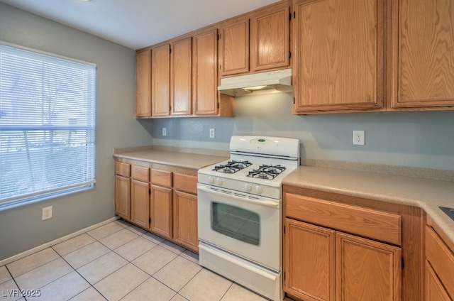 kitchen with light tile patterned flooring, white gas range, and a healthy amount of sunlight