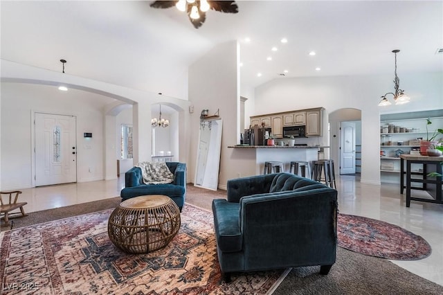 tiled living room featuring a towering ceiling and ceiling fan with notable chandelier