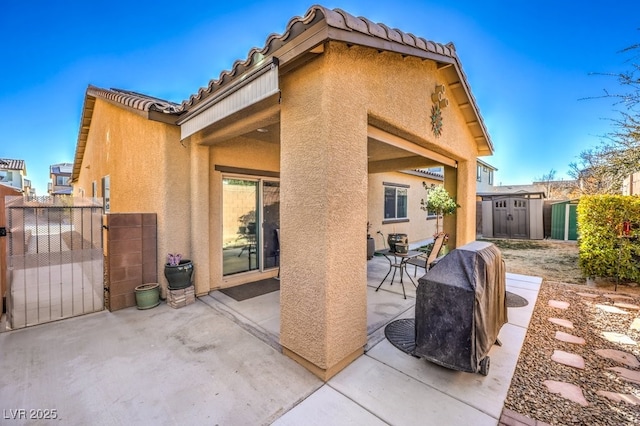 rear view of property with a shed and a patio area