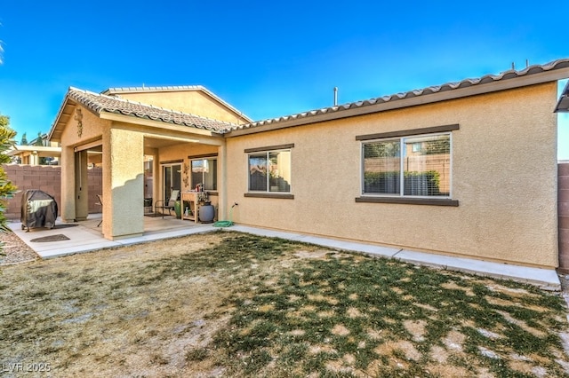 back of property with a lawn and a patio