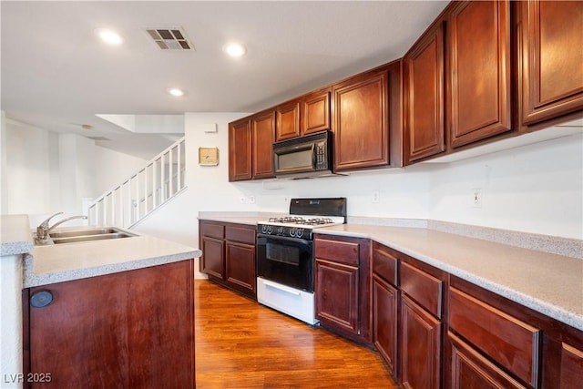 kitchen featuring white gas range, dark hardwood / wood-style floors, and sink