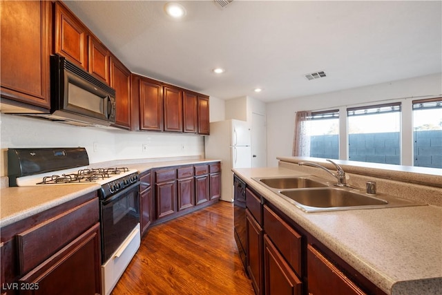 kitchen featuring black appliances, dark wood-type flooring, and sink