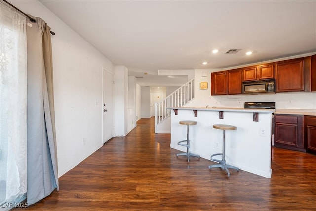 kitchen with dark hardwood / wood-style floors, a center island, and a breakfast bar area