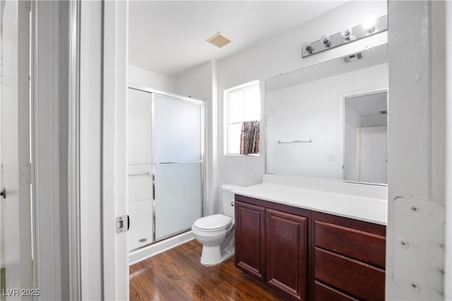 bathroom featuring hardwood / wood-style flooring, an enclosed shower, vanity, and toilet