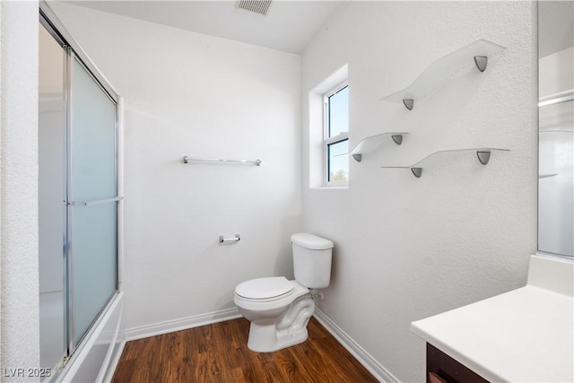 full bathroom with toilet, vanity, wood-type flooring, and combined bath / shower with glass door