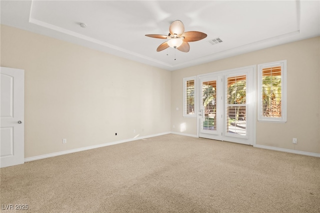 carpeted empty room featuring a raised ceiling and ceiling fan