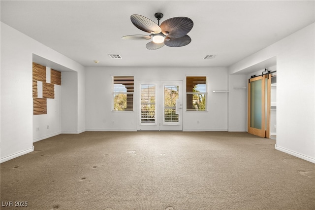 unfurnished living room featuring ceiling fan, carpet, and a barn door