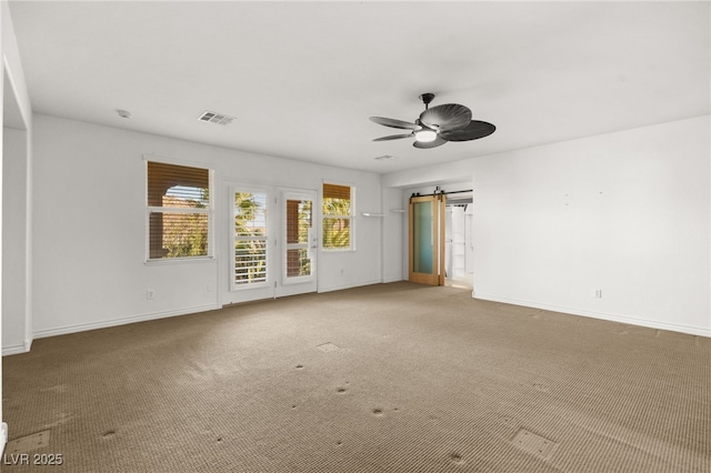 unfurnished room featuring ceiling fan, carpet flooring, and a barn door