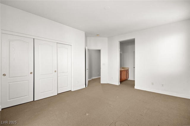 unfurnished bedroom with light colored carpet, connected bathroom, and a closet