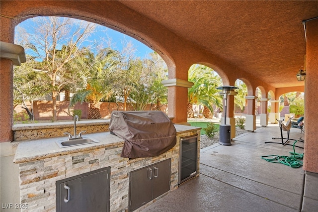 view of patio with sink, beverage cooler, an outdoor kitchen, and grilling area