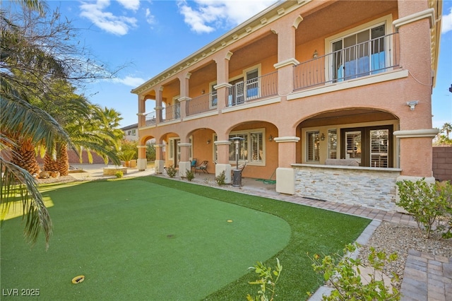 rear view of property featuring a balcony and a patio area