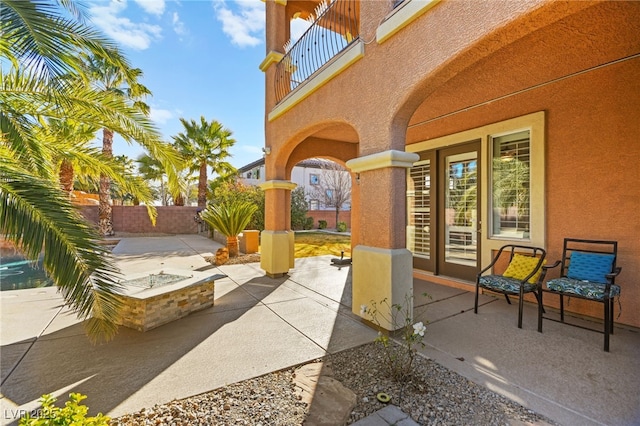 view of patio with a balcony and a fire pit