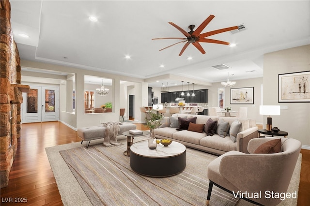 living room featuring ceiling fan with notable chandelier and hardwood / wood-style floors