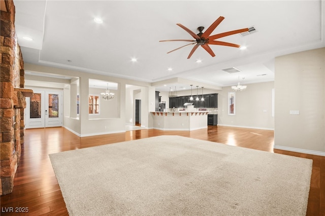 unfurnished living room featuring ceiling fan with notable chandelier and wood-type flooring