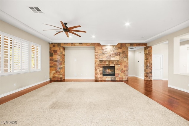 unfurnished living room featuring ceiling fan, hardwood / wood-style floors, and a stone fireplace