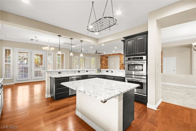 kitchen featuring ceiling fan with notable chandelier, a kitchen island, a kitchen bar, stainless steel appliances, and kitchen peninsula