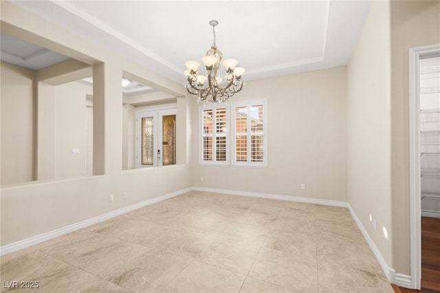 empty room featuring a tray ceiling and a notable chandelier