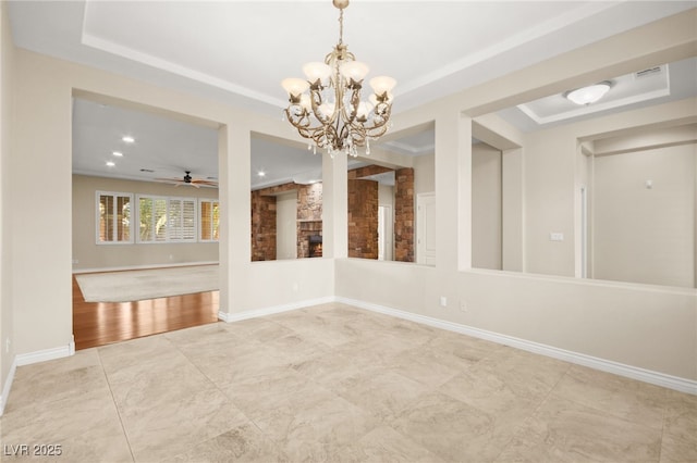 unfurnished room with ceiling fan with notable chandelier and a tray ceiling