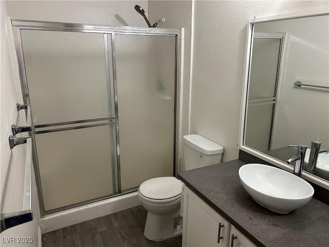 bathroom with walk in shower, vanity, toilet, and hardwood / wood-style floors