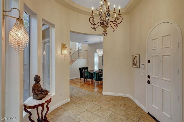 tiled entrance foyer featuring a notable chandelier and a tray ceiling