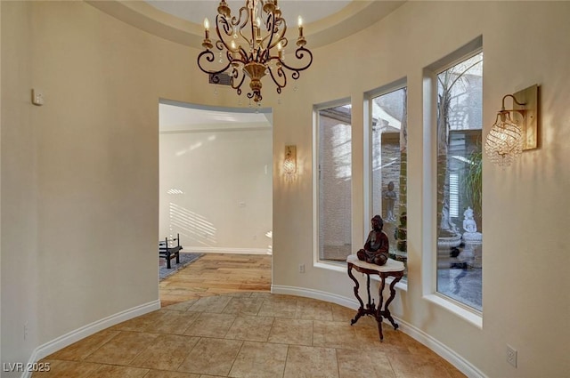 interior space with a tray ceiling and a chandelier