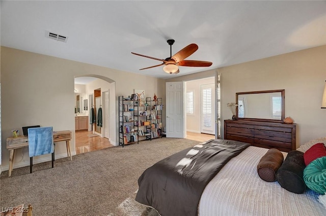 bedroom featuring ensuite bath, ceiling fan, and light carpet