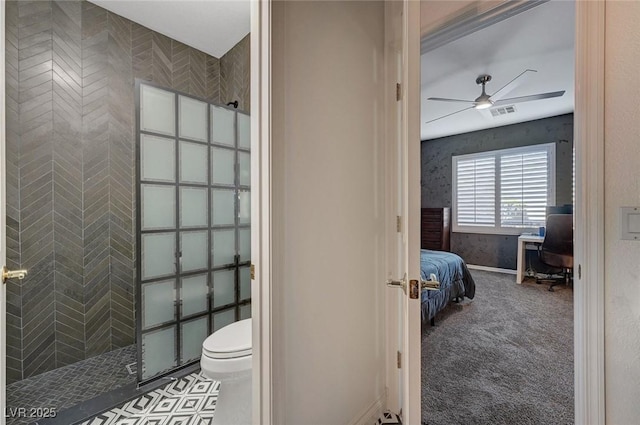 bathroom featuring toilet, ceiling fan, and a tile shower