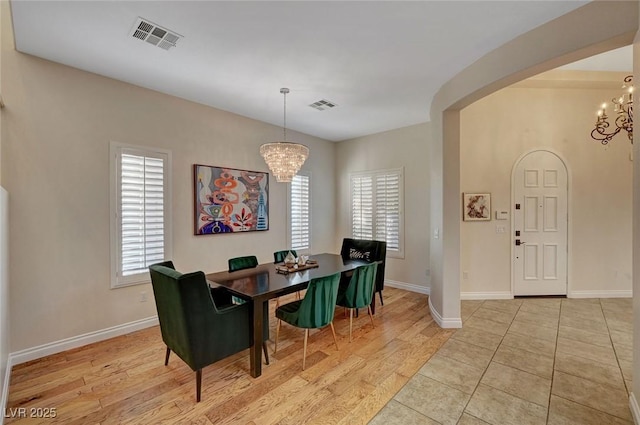 dining room with a wealth of natural light, light hardwood / wood-style flooring, and an inviting chandelier