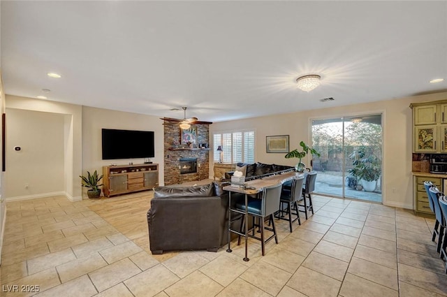 tiled living room featuring ceiling fan, a wealth of natural light, and a stone fireplace