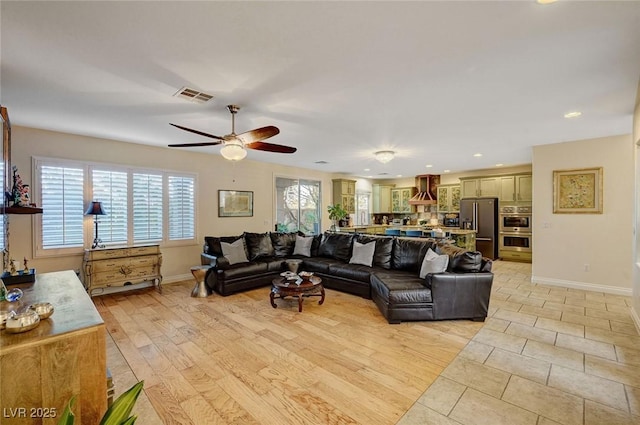 living room featuring light wood-type flooring, ceiling fan, and a healthy amount of sunlight