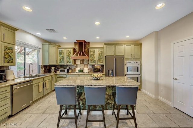 kitchen featuring tasteful backsplash, a kitchen island, sink, stainless steel appliances, and wall chimney exhaust hood