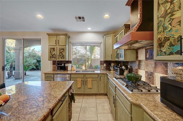 kitchen with wall chimney range hood, decorative backsplash, sink, stainless steel appliances, and light tile patterned floors