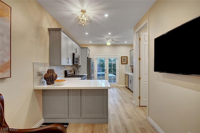 kitchen with backsplash, gray cabinets, kitchen peninsula, stainless steel appliances, and french doors