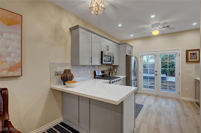 kitchen featuring gray cabinets, decorative backsplash, kitchen peninsula, stainless steel appliances, and french doors