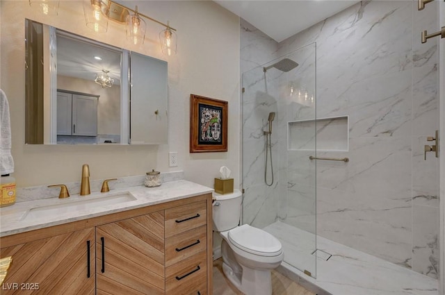 bathroom with toilet, vanity, and tiled shower