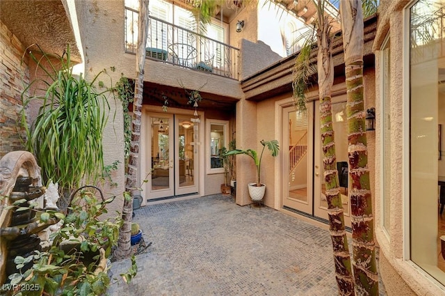 view of exterior entry featuring a patio area, french doors, and a balcony