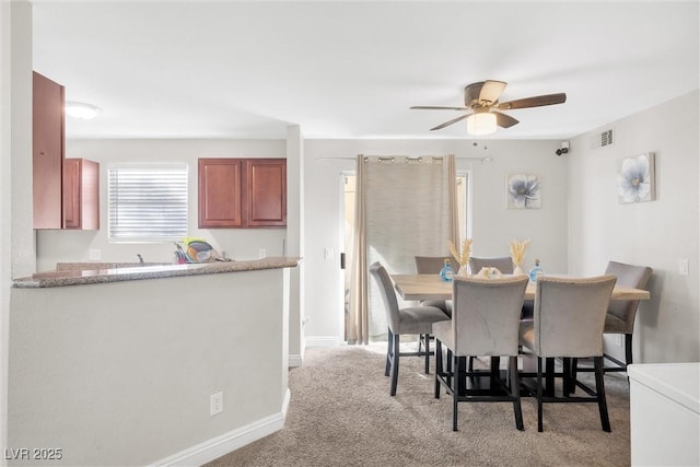 carpeted dining area with ceiling fan