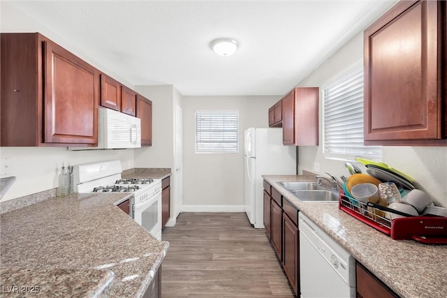 kitchen featuring light wood-type flooring, sink, light stone counters, and white appliances