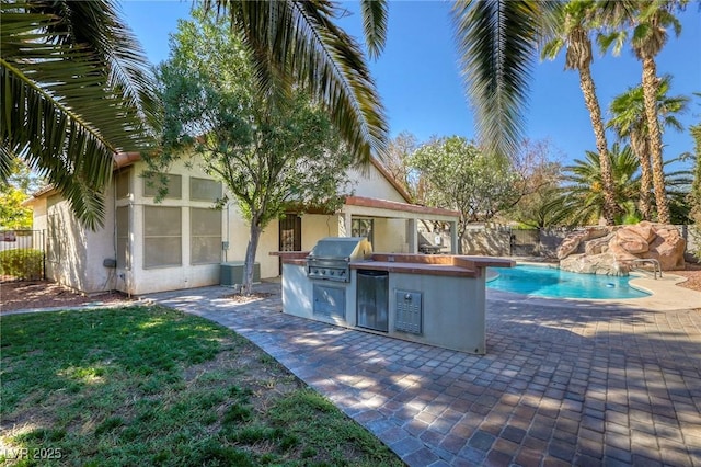 view of pool with an outdoor kitchen, area for grilling, and a patio