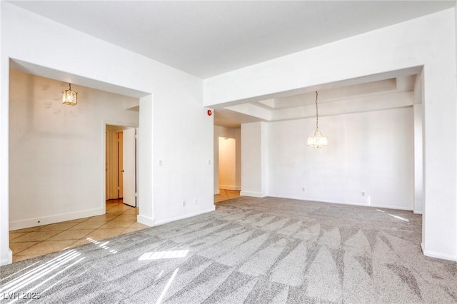 carpeted spare room with a chandelier