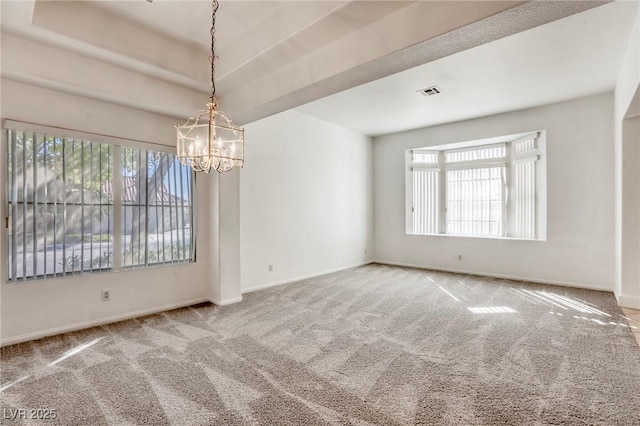 carpeted spare room with an inviting chandelier