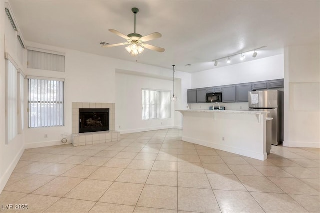 kitchen with light stone counters, light tile patterned floors, ceiling fan, and stainless steel refrigerator