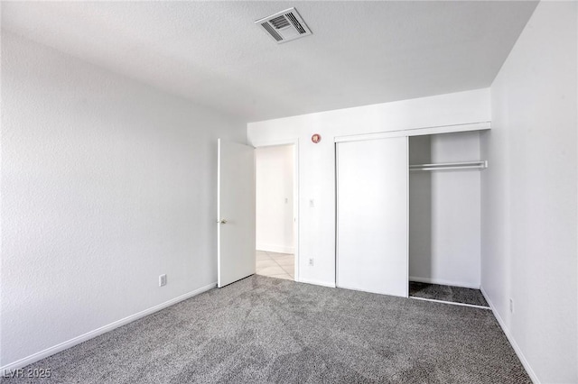 unfurnished bedroom with light colored carpet and a closet