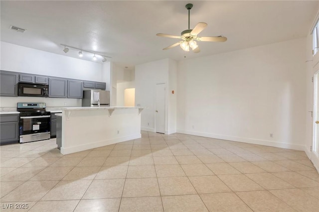 kitchen featuring light tile patterned floors, a kitchen breakfast bar, appliances with stainless steel finishes, and gray cabinetry